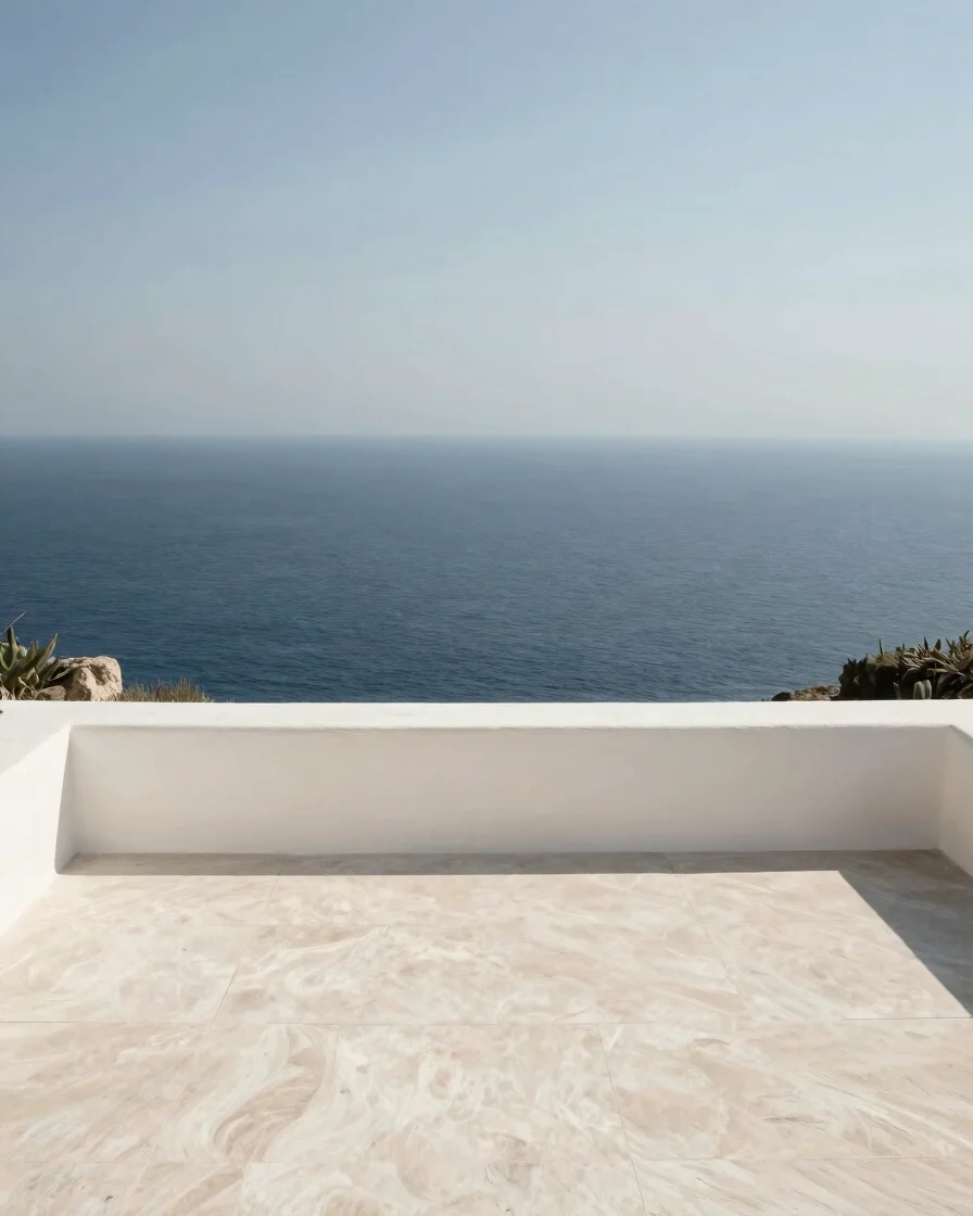 Wide editorial photograph of a sunlit private villa terrace overlooking a calm deep-blue ocean, soft natural daylight, u
